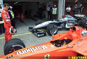 Michael Schumacher looks at his car sitting in parc ferme