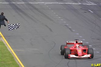 Alan Jones waves the checquered flag at Michael Schumacher