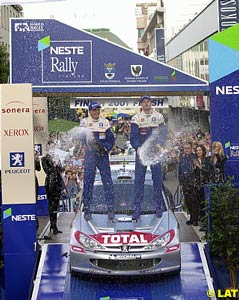 Marcus Gronholm and Timo Rautiainen spray champagne from the bonnet of their winning 206