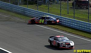 Jeff Gordon slides along the grass as the damaged car of Kevin Harvick drives past