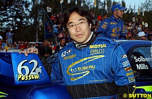 Production Car winner Toshihiro Arai stands beside one of the '62 Possum' stickers that the Subarus ran during the rally