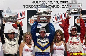 Paul Tracy holds his trophy aloft with fellow podium finishers Bruno Junqueira and Michel Jourdain Jr