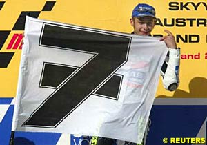 Valentino Rossi holds the black and white number seven flag on the podium