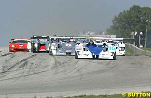 The field storms into turn one at the start, led by Butch Leitzinger in the Lola-MG
